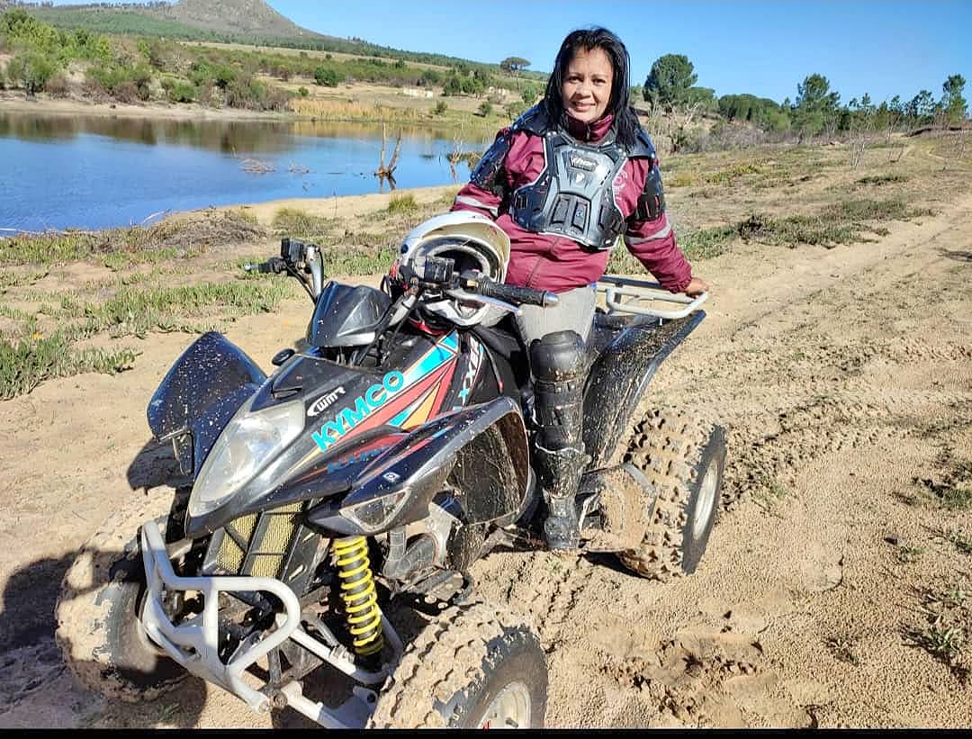 Regina Clarke on a quad bike beside a dam
